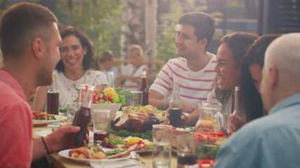 Big Family Garden Party Celebration, Gathered Together at the Table Relatives and Friends, Young and Elderly are Eating, Drinking, Passing Dishes, Joking and Having Fun. - Powered by Adobe
