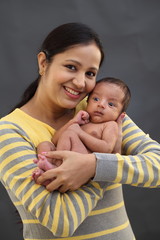 Cheerful mother playing with newborn baby