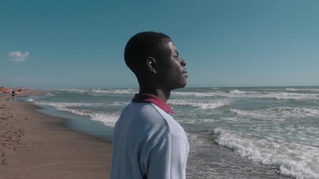 portrait of Young african migrant alone on the beach thinking his homeland. Migration,Africa