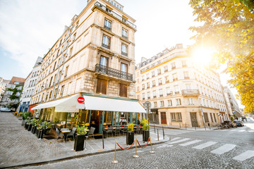 Plakat Street view with beautiful buildings and cafe terrace during the morning light in Paris