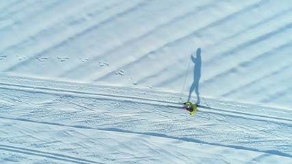 AERIAL: Flying above energetic woman skiing down the narrow trails on sunny day.
