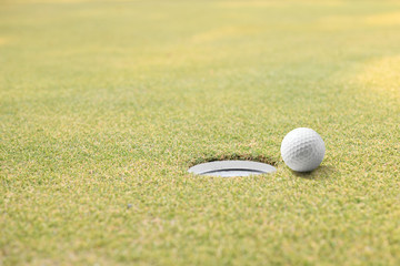 Golf ball and golf hole on green grass with copy space