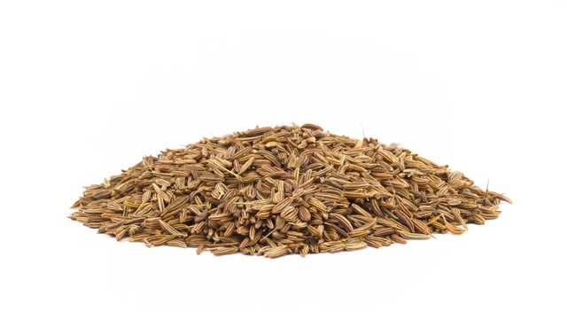 Caraway seeds heap. Rotating on the turntable. Isolated on the white background. Close up. Macro.