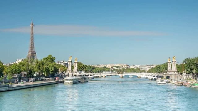 The Pont Alexandre III, famous arch bridge over the river Seine in Paris, France. White clouds move across the blue sky. 