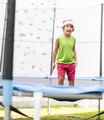 Little boy with Santa hat jumping on trampoline