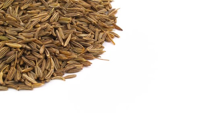 Half frame. Pile of caraway seeds. Vertically rotating. Isolated on the white background. Close up. Macro.
