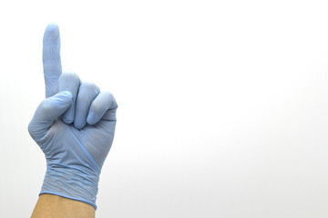 The surgeon's hand in a blue medical glove, showing a sign on an isolated background.