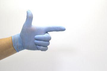 The surgeon's hand in a blue medical glove, showing a sign on an isolated background.