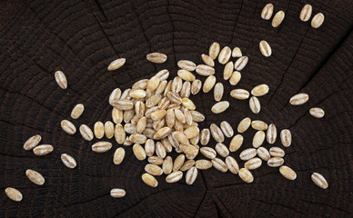Heap of pearl barley on black wooden background. Top view