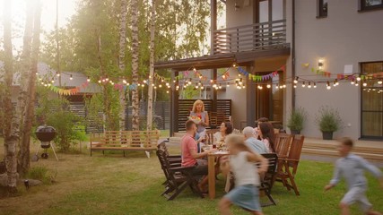 Big Family Garden Party Celebration, Gathered Together at the Table Family, Friends and Children. People are Drinking, Passing Dishes, Joking and Having Fun. Panoramic Camera Shot.