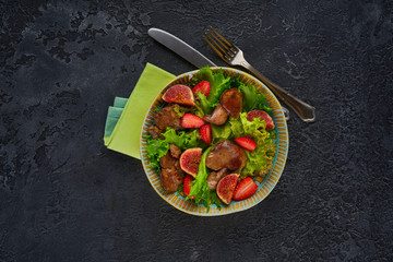 Green salad with liver and strawberry on dark rustic background