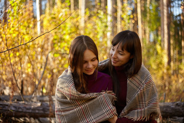 Cute portrait of mother and daughter in the autumn forest.