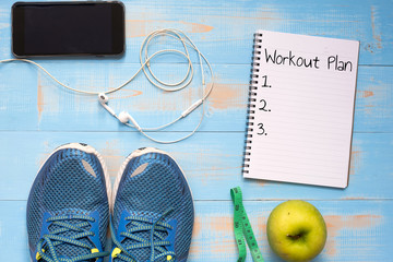 Fototapeta na wymiar Fitness, Dieting, healthy and lifestyles Concept, Sport Item or exercise accessories, running shoes, apples measuring tape and smartphone with headphone on blue wooden background. copy space for text