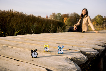 Three small alarm retro clocks on wooden surface. Autumn abstract photo.