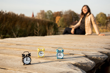 Three small alarm retro clocks on wooden surface. Autumn abstract photo.