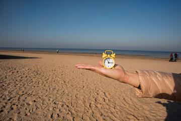 Vintage black alarm clock on autumn leaves. Time change abstract photo.
