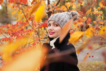 Portrait of a beautiful and dreamy girl in a knitted hat in autumn