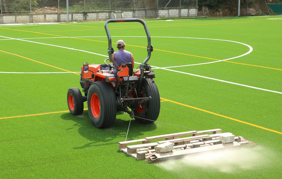 tractor preparando el nuevo c&eacute;sped artificial de un campo de f&uacute;tbol, poniendo arena