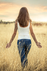 young pretty girl on the dry field at sunset