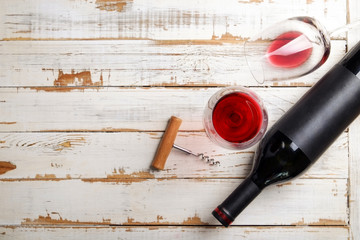 Vintage bottle of red wine with blank matte black label, poured glass, corkscrew & grapes, grunged...