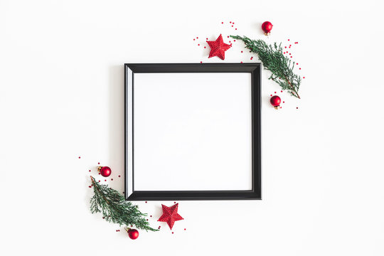 Christmas composition. Photo frame, red decorations, fir tree branches on white background. Christmas, winter, new year concept. Flat lay, top view, copy space