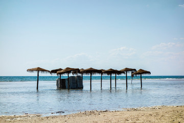 Sombrillas de paja en la playa inundados por la subida del mar