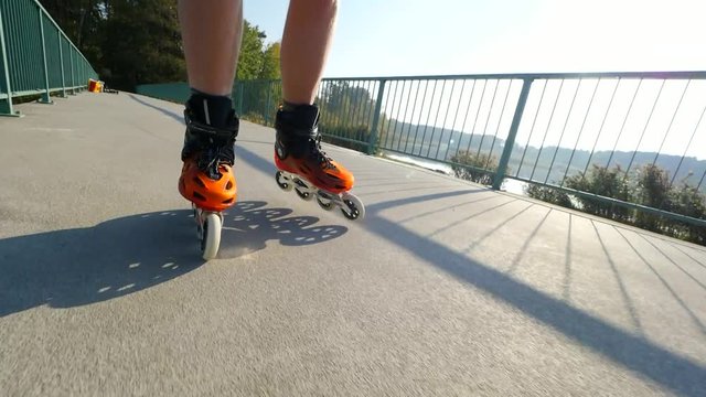 Close up of inline roller skater legs.  Skating in hard shell hi-tech skates on lake bridge road. 