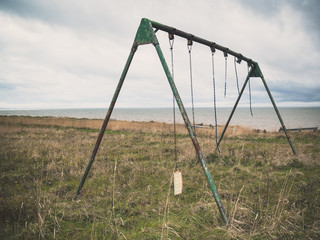 Fototapeta na wymiar Abandoned swingset in an overgrown park