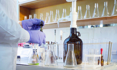 Chemical analysis laboratory. Close up hands of the scientist chemist dropping a indicator to...