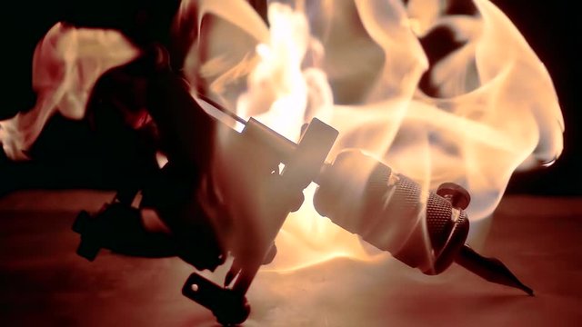 Close-up shot of a burning tattoo machine on the table.