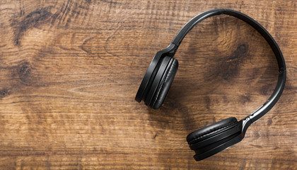 wireless Black headphones on wooden table background with copy space. top view