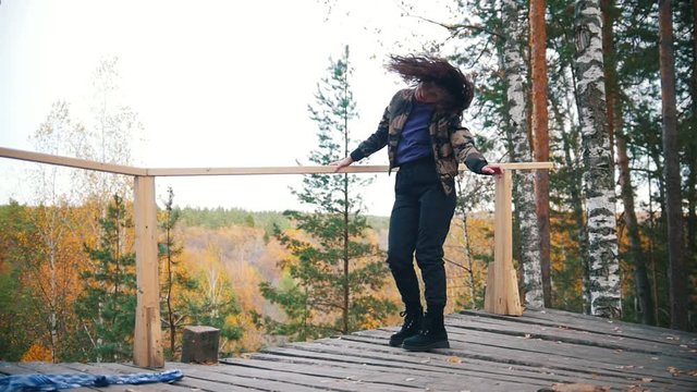 Happy young woman dancing on platform. Flying hair. Forest on the background. Slow motion