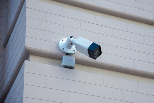 External surveillance camera mounted on the corner of a brick building. Camera mount external surveillance. Video camera to monitor the street.