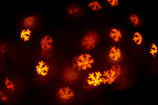 bokeh of glowing garland on a black background in the shape of snowflakes, the concept of winter and Christmas - Powered by Adobe