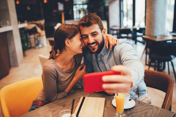 Young happy couple at a date making selfie in a coffee shop