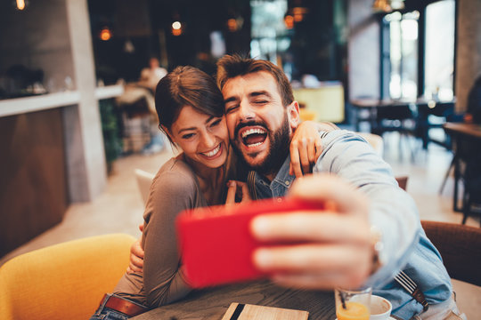 Young happy couple at a date making selfie in a coffee shop