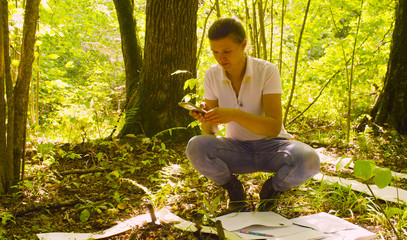 The woman ecologist shooting plants inside the square marking site by smartphone. Field work