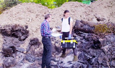 Crane shot. Two scientists ecologists standing at the place where the forest burned down. Field work