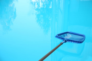 Naklejka na ściany i meble Cleaning outdoor pool with scoop net, closeup