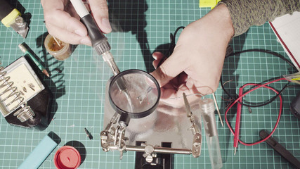 Top view. Close up. Repairing of a wire for electronic devices. Man solderes a wire