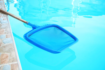 Fototapeta na wymiar Cleaning outdoor pool with scoop net, closeup
