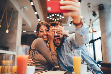 Young happy couple at a date making selfie in a coffee shop