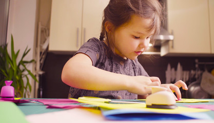 Scrapbooking. Little girl doing a postcard. She is glueing colored paper. Children's creativity, handicraft