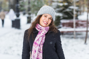 City, fashion and winter concept - Beautiful happy woman dressed in black coat, pink scarf and grey hat