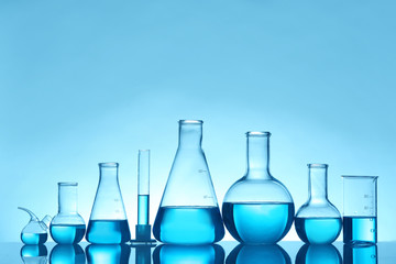Laboratory glassware with liquid on table against color background. Chemical analysis