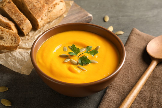 Delicious pumpkin cream soup in bowl on gray background