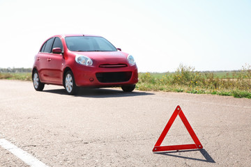Emergency stop sign and broken car on background