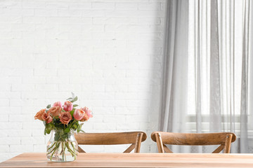 Vase with beautiful flowers as element of interior design on table in room. Space for text