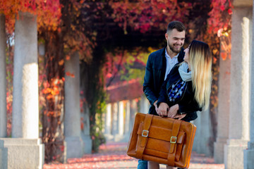 young couple with suitcase at alley in autumn season time