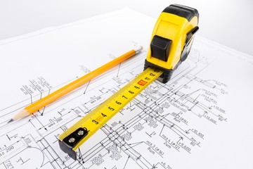 Measuring tape and pencil on top of architectural plans